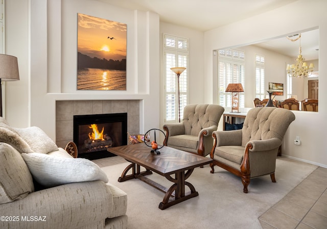 tiled living room featuring a tile fireplace, baseboards, and an inviting chandelier