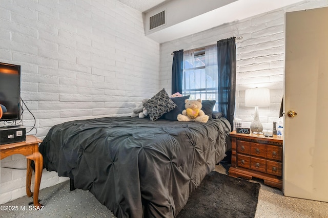 bedroom featuring brick wall, visible vents, and speckled floor