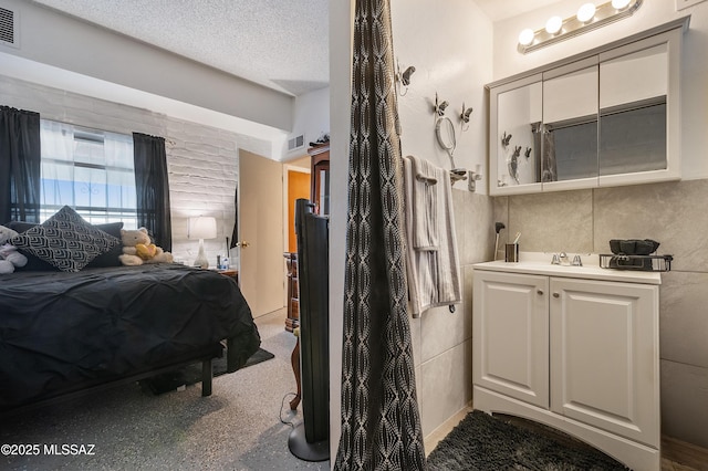 bedroom with a textured ceiling, visible vents, and tile walls