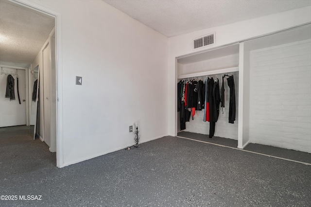 unfurnished bedroom with a closet, visible vents, a textured ceiling, and dark speckled floor