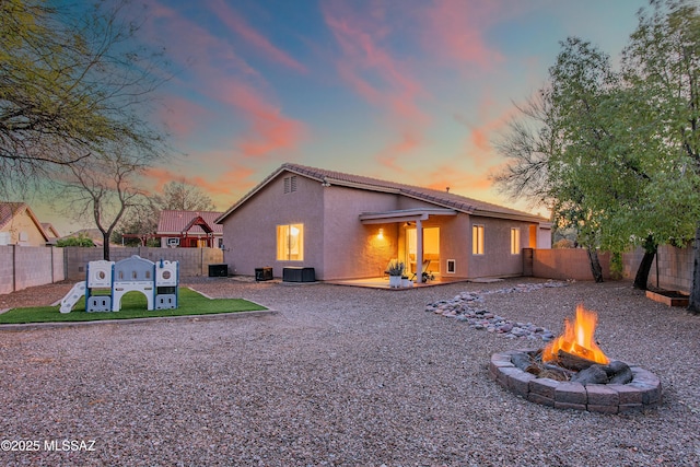 back of property with a fire pit, a patio, a fenced backyard, central AC, and stucco siding