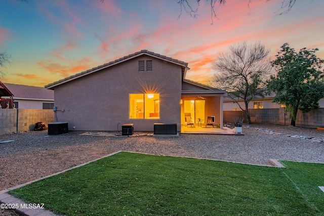 back of property featuring a yard, a patio, stucco siding, central AC unit, and a fenced backyard