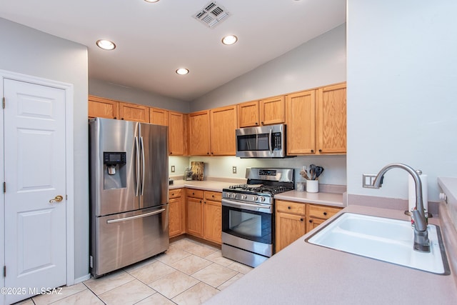 kitchen with light countertops, visible vents, appliances with stainless steel finishes, vaulted ceiling, and a sink