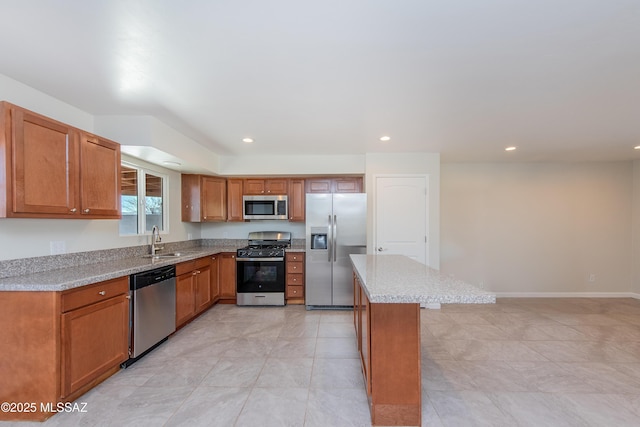 kitchen with brown cabinetry, a center island, stainless steel appliances, a sink, and recessed lighting