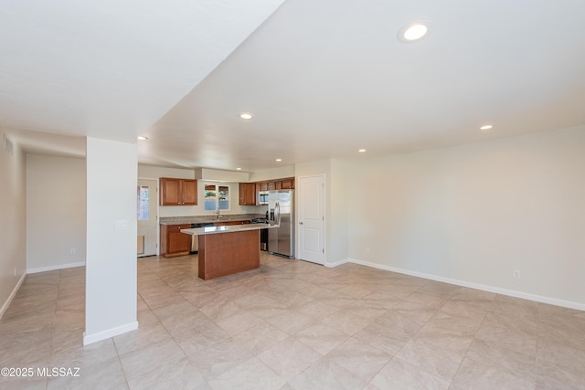 kitchen with brown cabinetry, a kitchen island, stainless steel appliances, and open floor plan