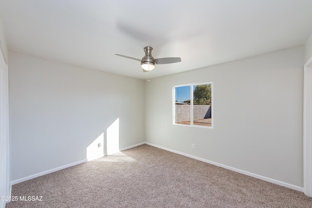 carpeted spare room featuring baseboards and a ceiling fan