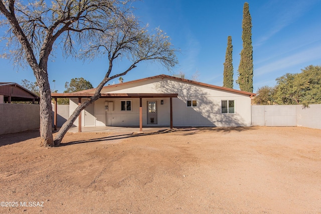 rear view of property featuring a patio area, a fenced backyard, and dirt driveway