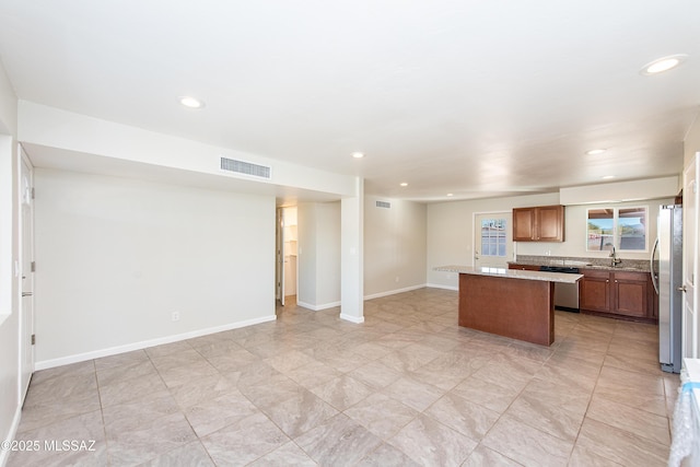 kitchen featuring stainless steel appliances, a kitchen island, visible vents, light countertops, and brown cabinetry