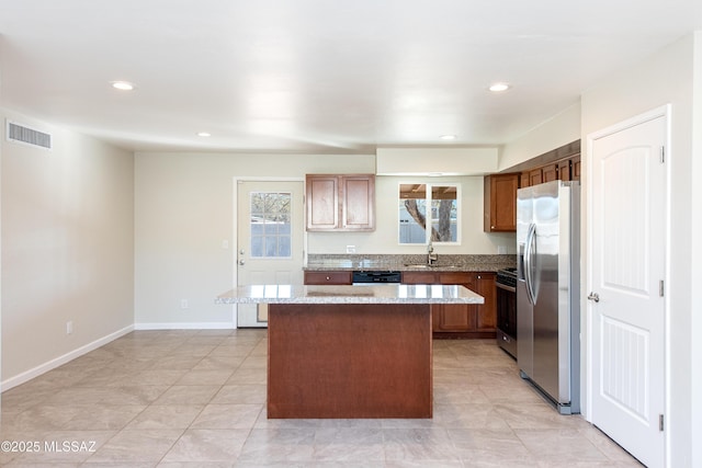 kitchen featuring a sink, visible vents, a center island, appliances with stainless steel finishes, and brown cabinets