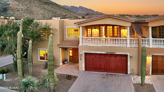 view of front of house with a balcony, a garage, and a mountain view