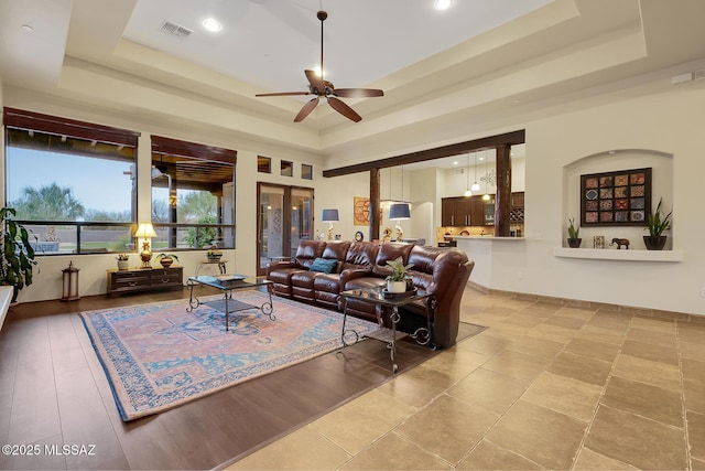 living room with a raised ceiling and ceiling fan