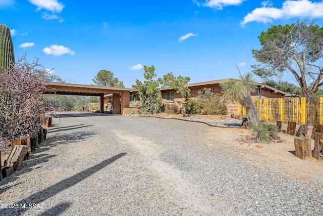 ranch-style home featuring an attached carport, driveway, and fence