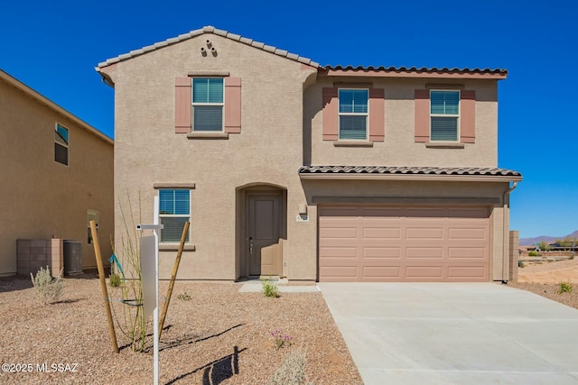 mediterranean / spanish home with a garage, a tiled roof, concrete driveway, and stucco siding