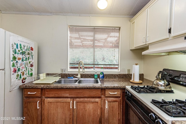 kitchen with white refrigerator, white cabinets, sink, and black gas range oven