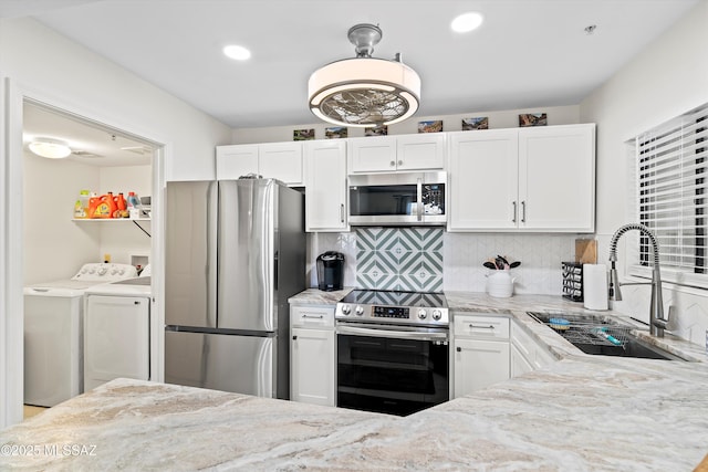 kitchen featuring light stone countertops, stainless steel appliances, white cabinetry, separate washer and dryer, and a sink