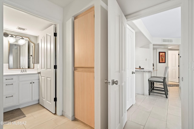 hallway featuring visible vents and a sink