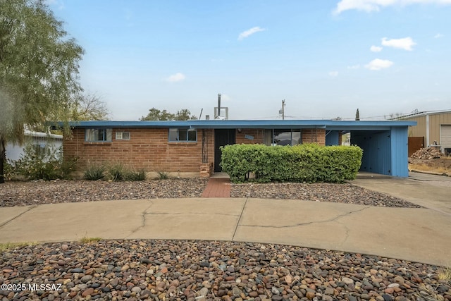 ranch-style home featuring a carport, concrete driveway, and brick siding