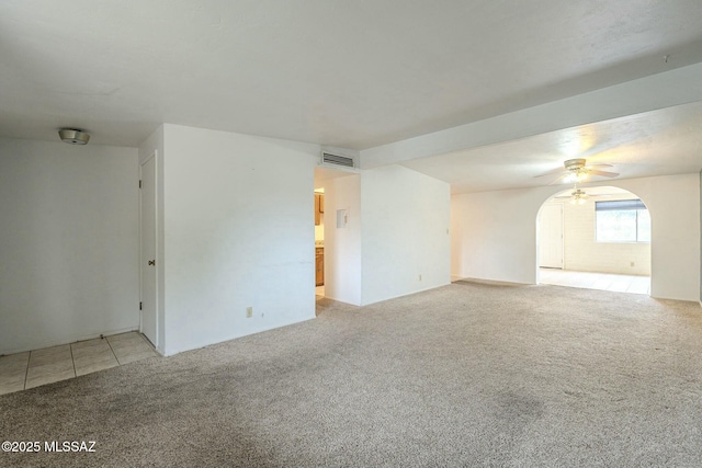 unfurnished room featuring visible vents, arched walkways, ceiling fan, tile patterned floors, and carpet