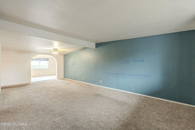 carpeted spare room with arched walkways, lofted ceiling with beams, and baseboards