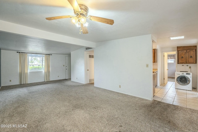 empty room featuring light carpet, light tile patterned floors, lofted ceiling, and washer / dryer