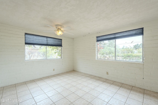 empty room featuring ceiling fan, a textured ceiling, and tile patterned floors