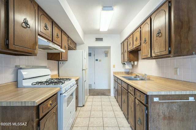 kitchen with white appliances, visible vents, light countertops, under cabinet range hood, and a sink