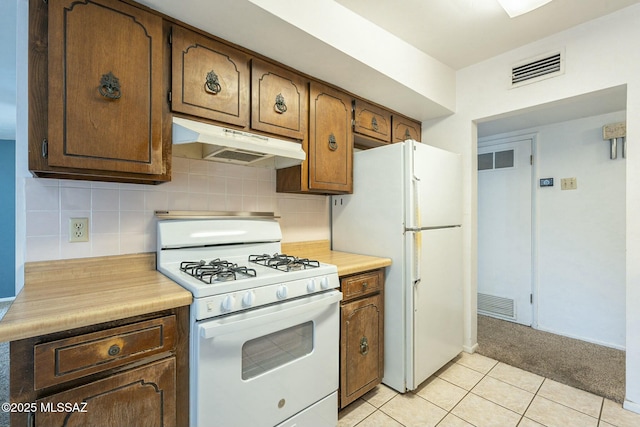 kitchen with white appliances, backsplash, visible vents, and under cabinet range hood