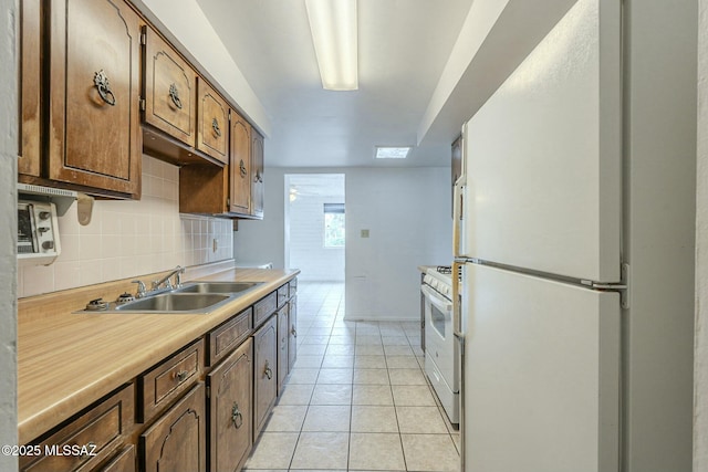 kitchen featuring light tile patterned flooring, white appliances, a sink, light countertops, and tasteful backsplash