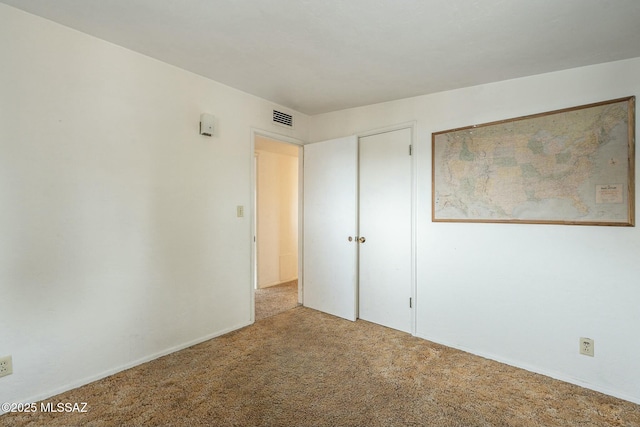 unfurnished bedroom with a closet, carpet, and visible vents