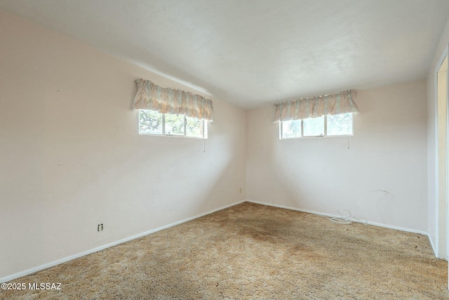 carpeted empty room featuring lofted ceiling and baseboards