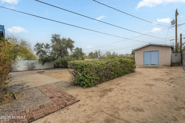 view of yard featuring a storage shed, fence, a patio, and an outbuilding