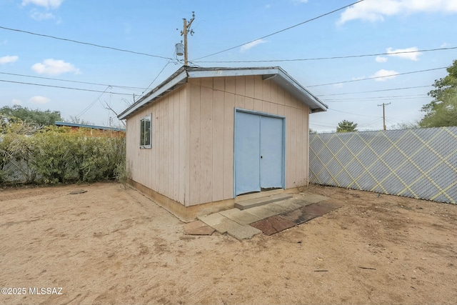 view of outbuilding with fence and an outbuilding