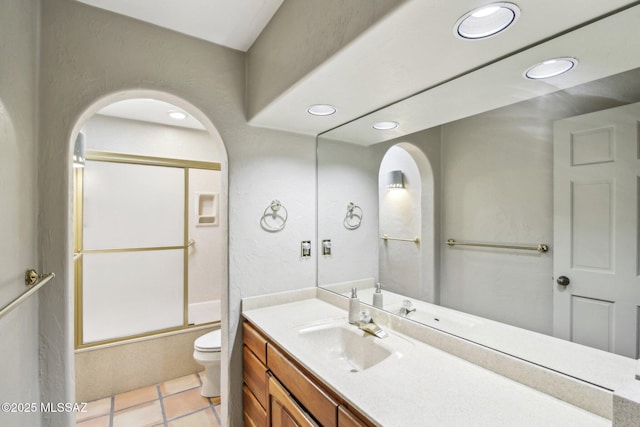 full bathroom with tile patterned floors, toilet, vanity, and bath / shower combo with glass door