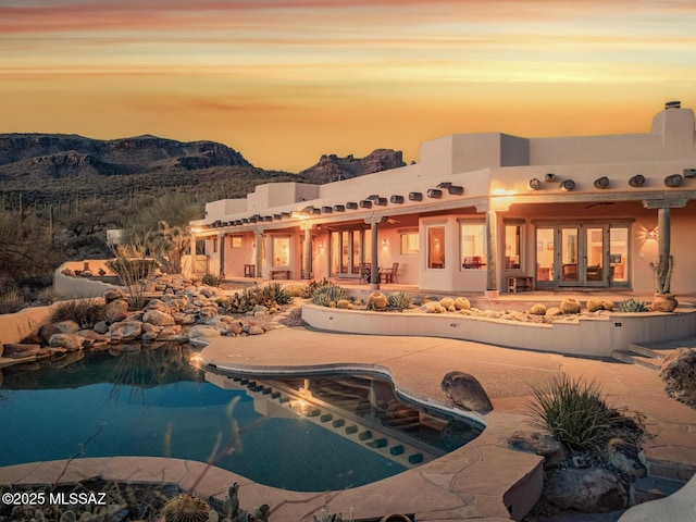 back of house with an outdoor pool, a mountain view, a patio, and stucco siding