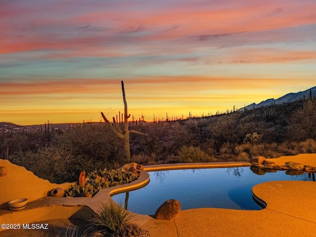 pool at dusk featuring a mountain view