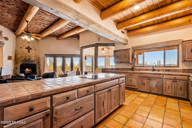 kitchen with ceiling fan, tile counters, open floor plan, wooden ceiling, and black electric cooktop