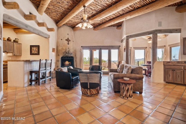 living area with beam ceiling, wood ceiling, light tile patterned flooring, and a ceiling fan