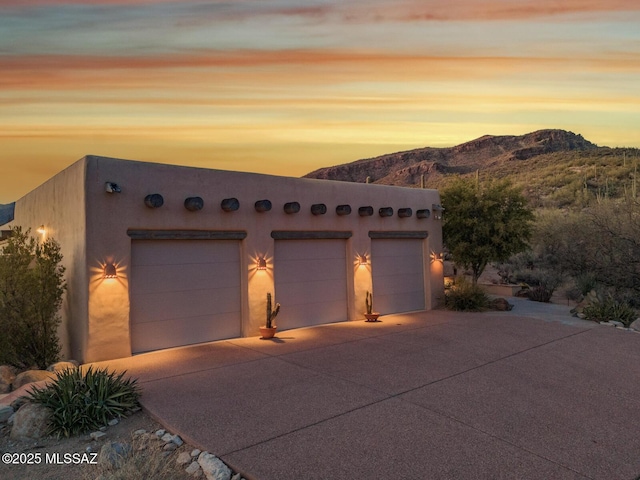 view of front of home featuring an outbuilding, a mountain view, concrete driveway, and an attached garage