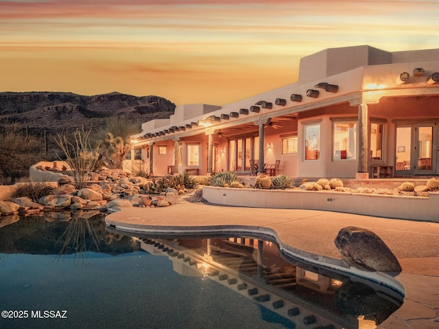 pool at dusk with a patio area, an outdoor pool, and a mountain view