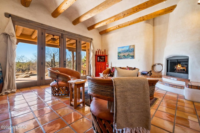 interior space with tile patterned flooring, beamed ceiling, a warm lit fireplace, and a high ceiling