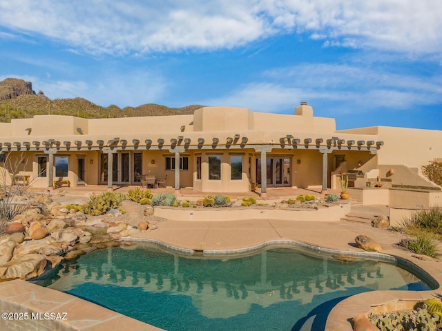 back of property featuring exterior kitchen, french doors, an outdoor pool, and a patio