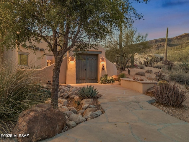 outdoor structure at dusk with a mountain view, concrete driveway, and an attached garage