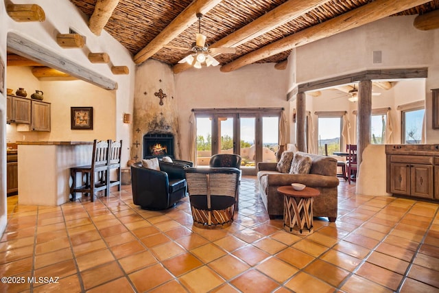 living room with light tile patterned floors, beamed ceiling, wooden ceiling, and a ceiling fan