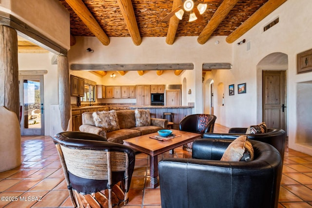 living room featuring beam ceiling, light tile patterned floors, and arched walkways