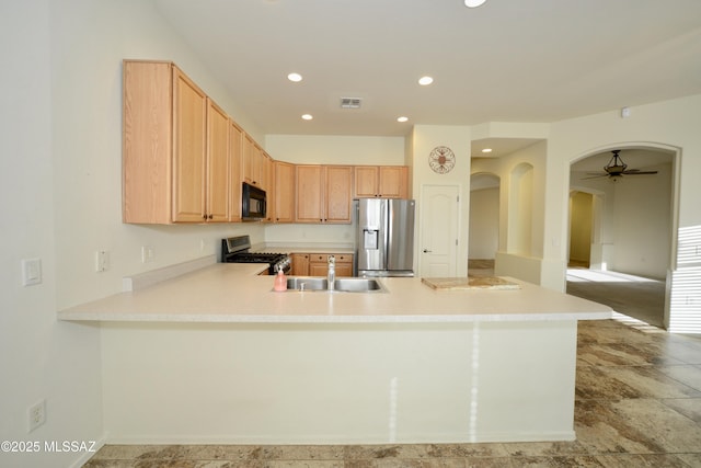 kitchen with stainless steel appliances, arched walkways, light countertops, and a peninsula