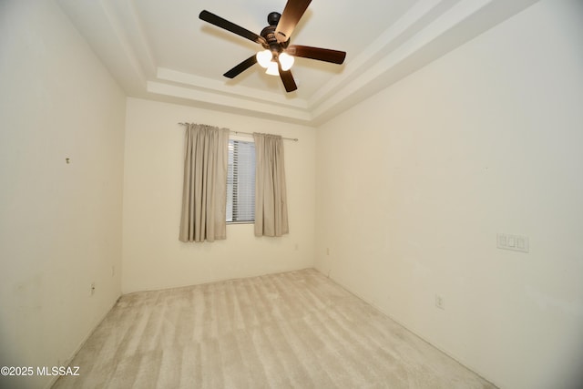 carpeted empty room featuring a tray ceiling and ceiling fan