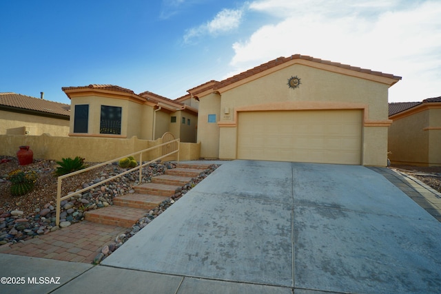 mediterranean / spanish house with an attached garage, fence, concrete driveway, a tiled roof, and stucco siding