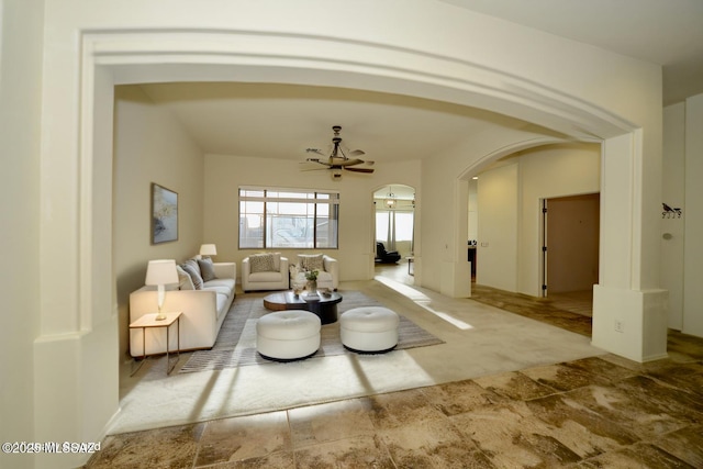 living area featuring carpet floors, arched walkways, and ceiling fan