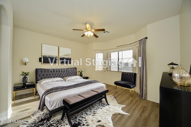 bedroom featuring a ceiling fan, visible vents, and wood finished floors