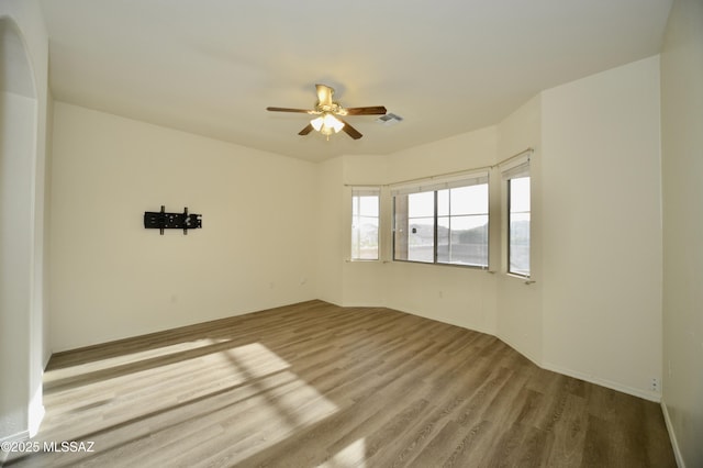 spare room featuring visible vents, ceiling fan, and wood finished floors